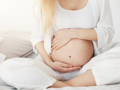 schwangere-sitzend-haelt-babybauch-mit-beiden-haenden-schwangerschaftsmassage-nadja-riedo-rheinau schwangere-sitzend-haelt-babybauch-mit-beiden-haenden-schwangerschaftsmassage-nadja-riedo-rheinau